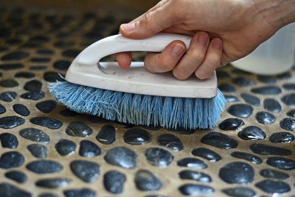 an image of a person cleaning pebble floor, close view