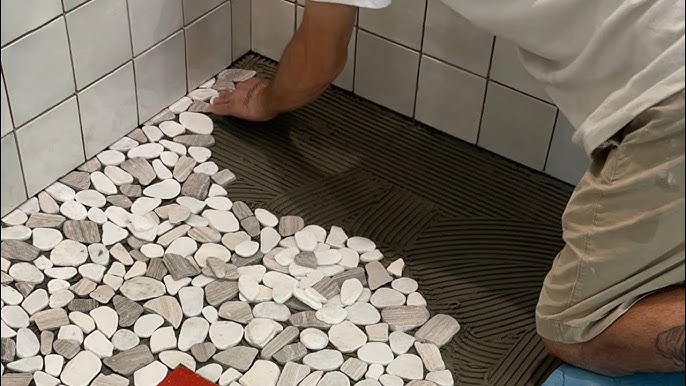 a person installing pebble floorin in bathroom