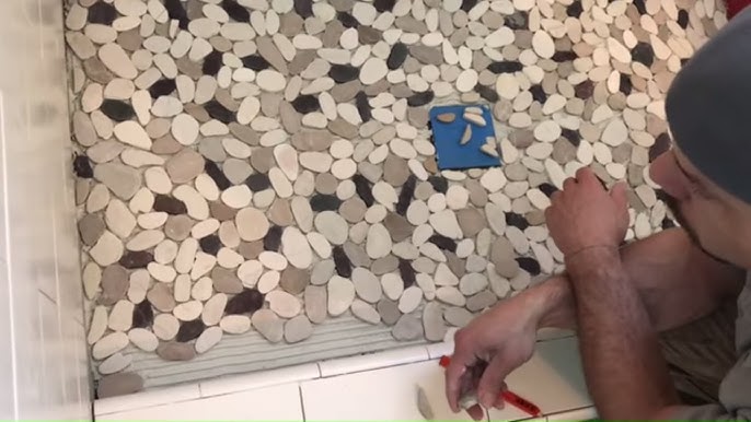 an image of a person installing pebbles floor in bathroom