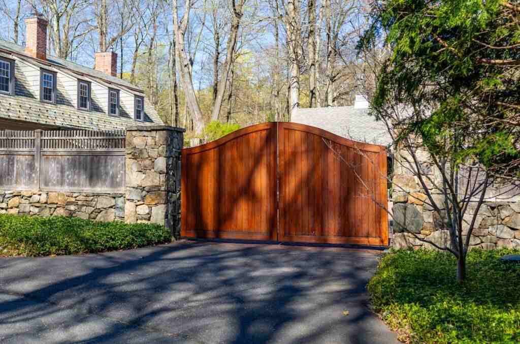 A wooden gate with stone pillar and tree on the each sides