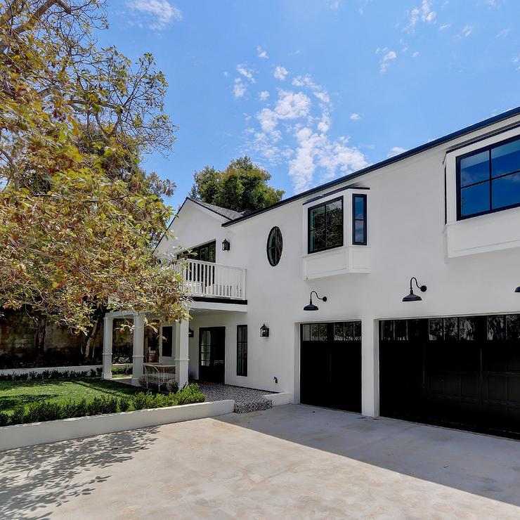 A white house and black garage door and glass window and celling light on wall