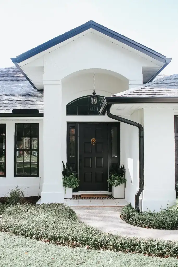 A white brick house and black roof and gutter and a celling lamp