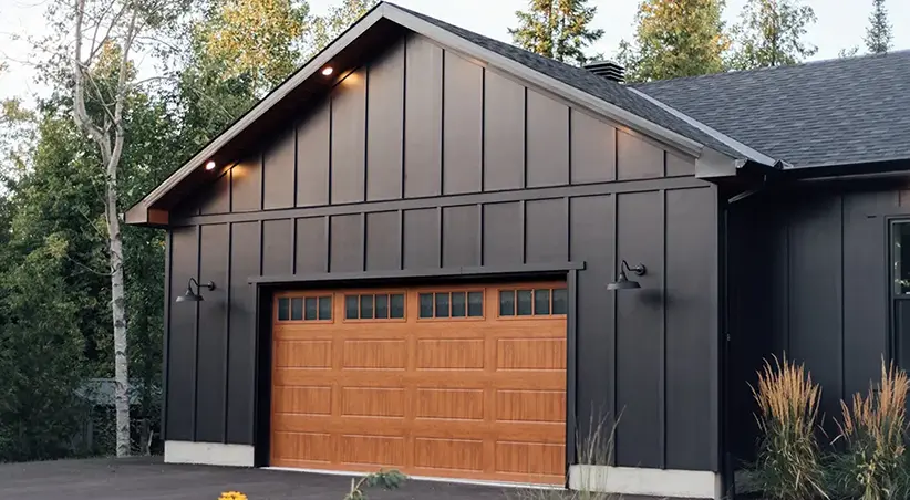 A black house and wooden garage and celling lights above the black roof