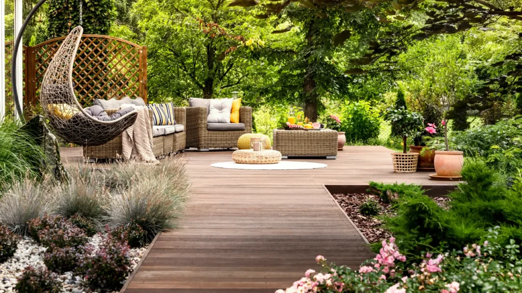 A wooden floor and flowers and plants each side on the floor and sofa some cushion placed on sofa