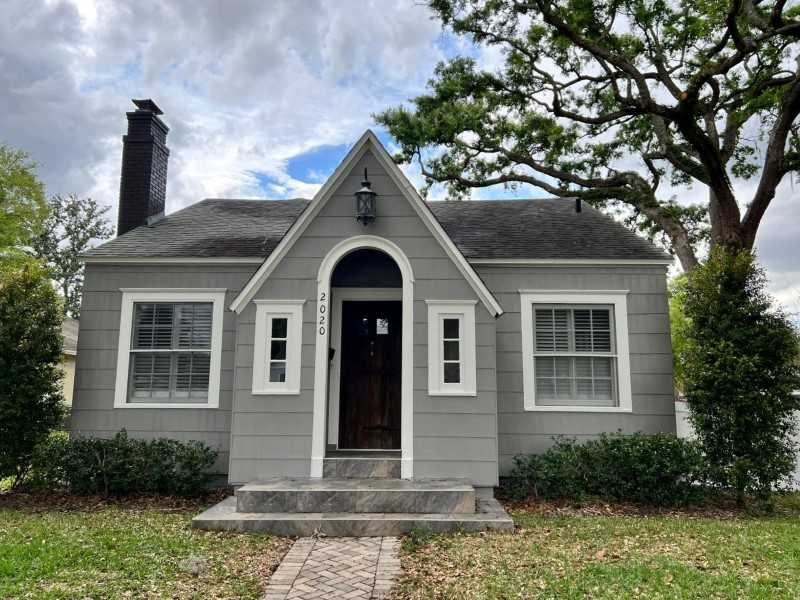 A gray house and black chimney and trim white framed window and a celling light above the wall
