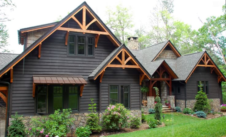 A wooden gable roof and black glass window and plants and garden outside of the house