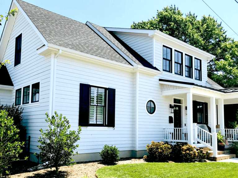 Black glass window and white railing and black shutter and garden outside of the house