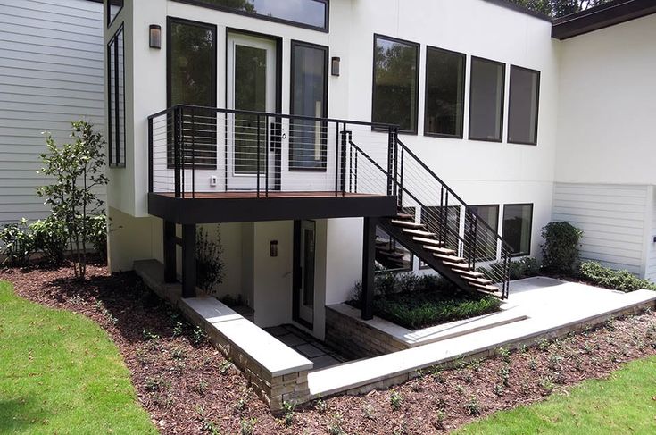 A black staircase and railings and white house and garden outside of the house