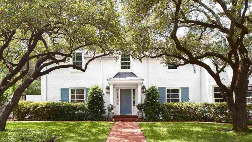 Blue shutter and white house and red pathway and garden outside of the house