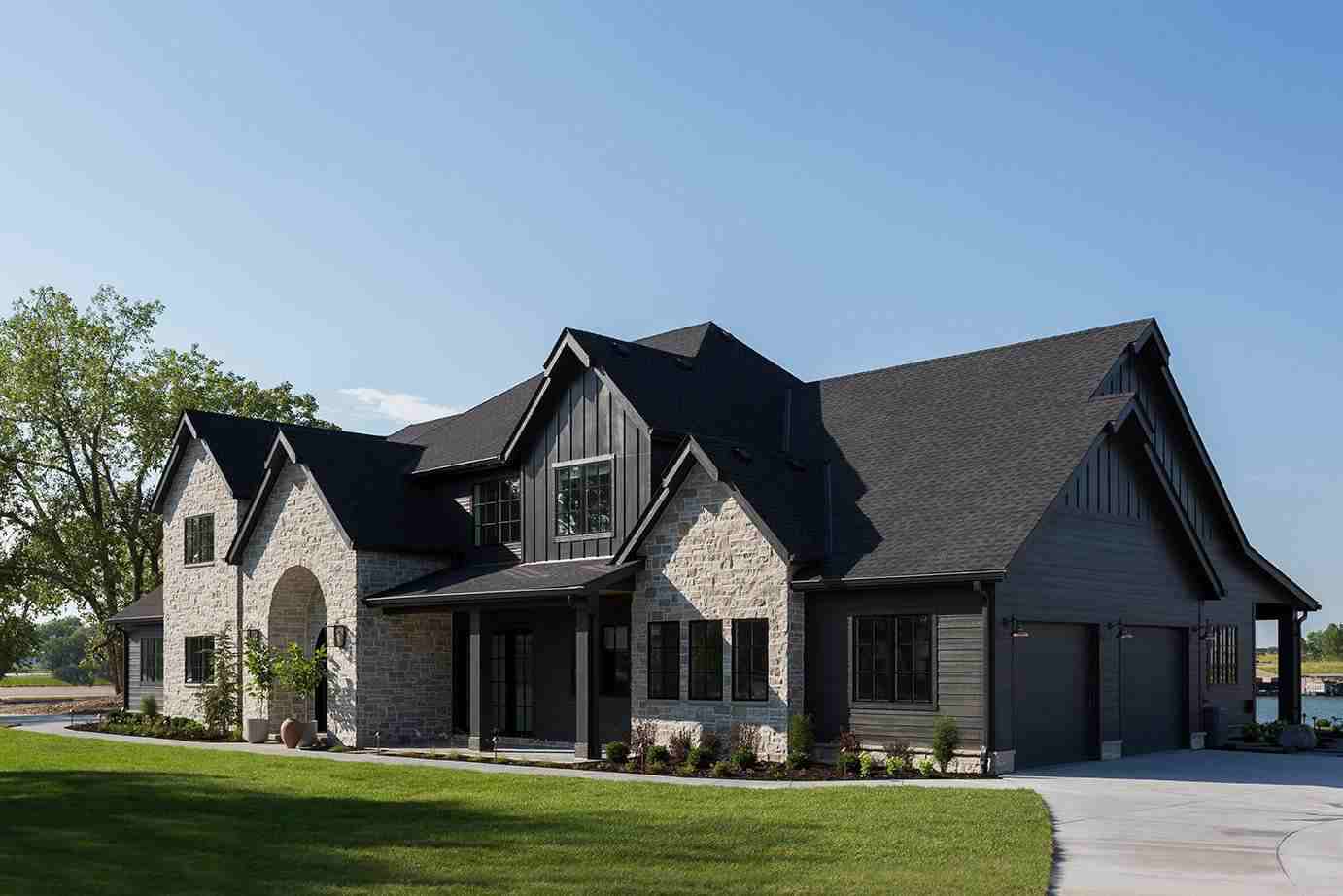 Black siding on the gray house and black framed window and garden outside of the house