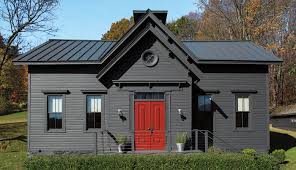 A red door and black house and glass window and garden outside of the house and celling lights on the wall
