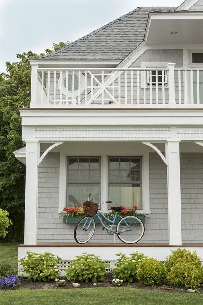 A light gray house and white balcony and glass window and blue bicycle