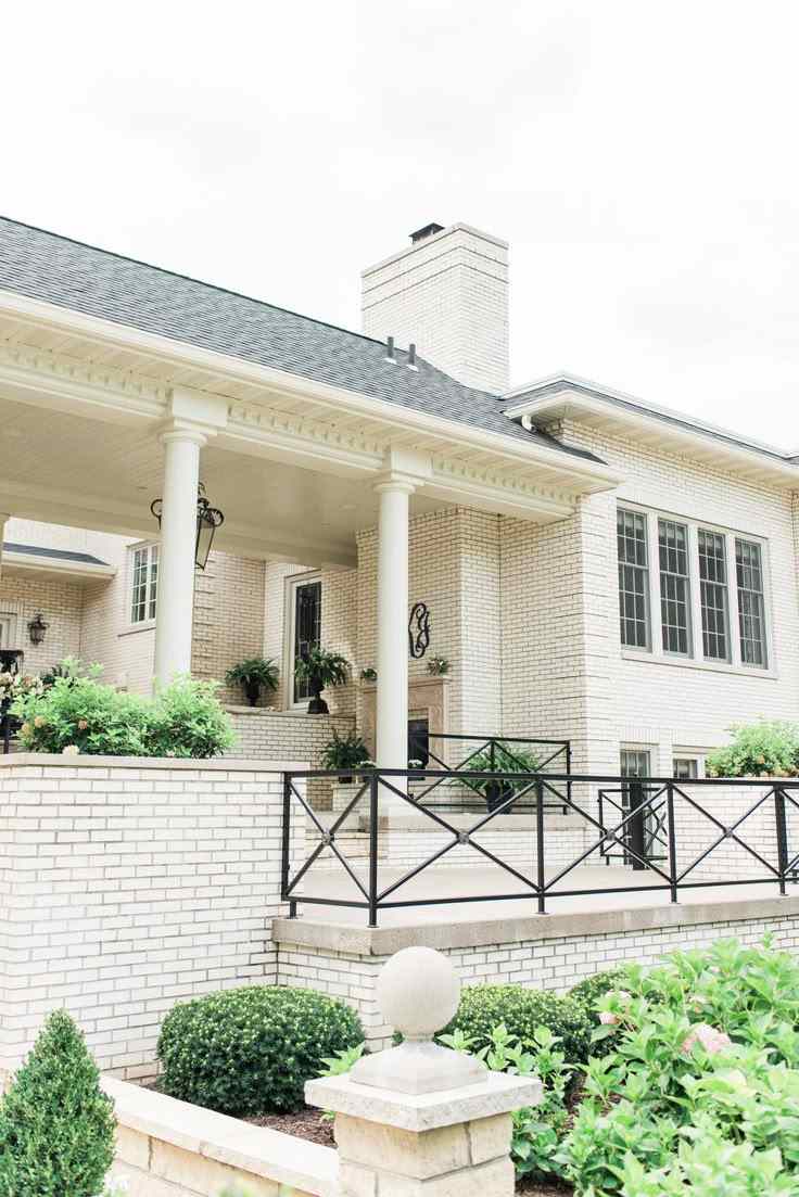 white stairs and black railing and red brick house wall