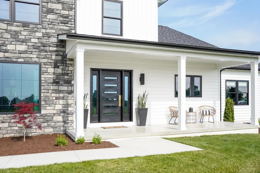 A white house and black glass door in centre and chairs in the corner