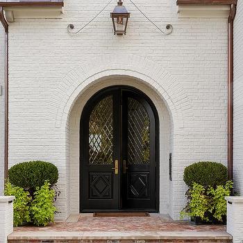 A white brick doorway and plants in the corner