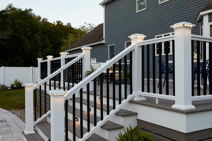 A white railings and lights on the pillars and black house