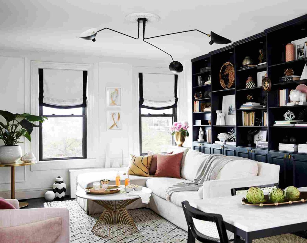 A white and black house and the roof in black and glass window with black trim and warm lights outside of the house
