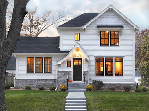 A white house and black roof and black trim window and warm lights and garden outside of the house