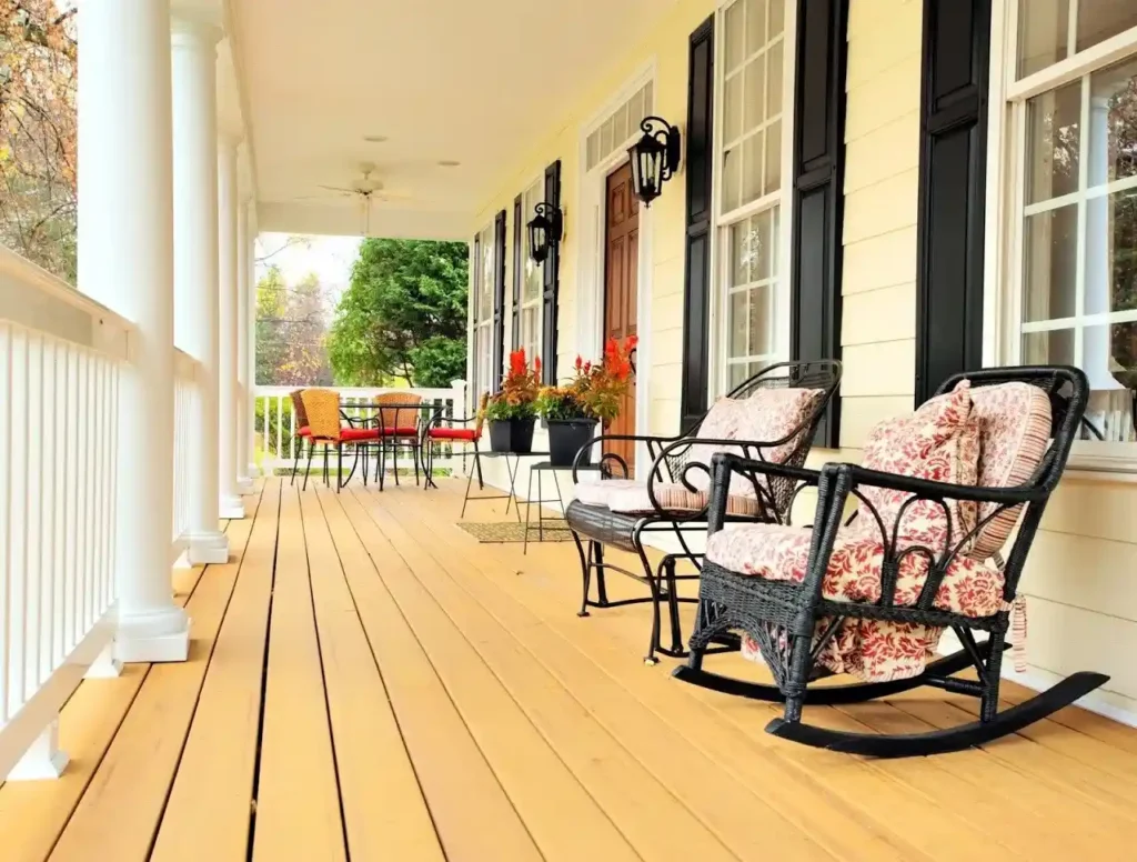 Creamy porch and white pillae and balcony and black chair on the floor ans lights on the wall