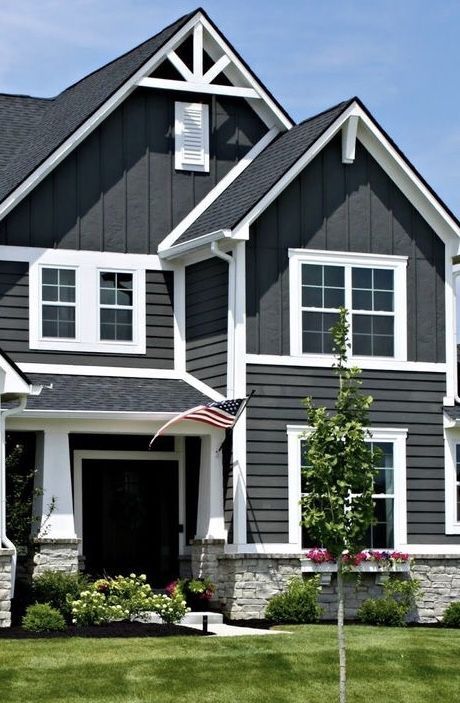 A gray house with white trim windows and garden outside of the house