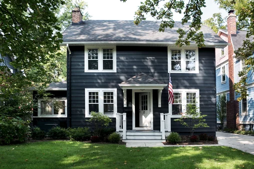 A black house and white trim window and garden outside of the house