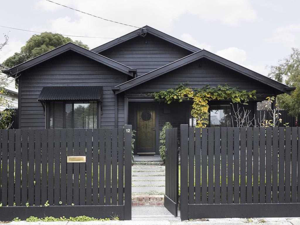 A black house and wood fencing around the house and glass window