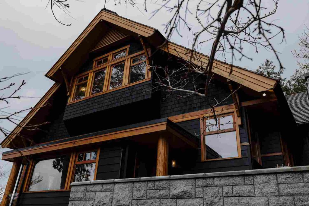 Black house with wood trim roof and glass window