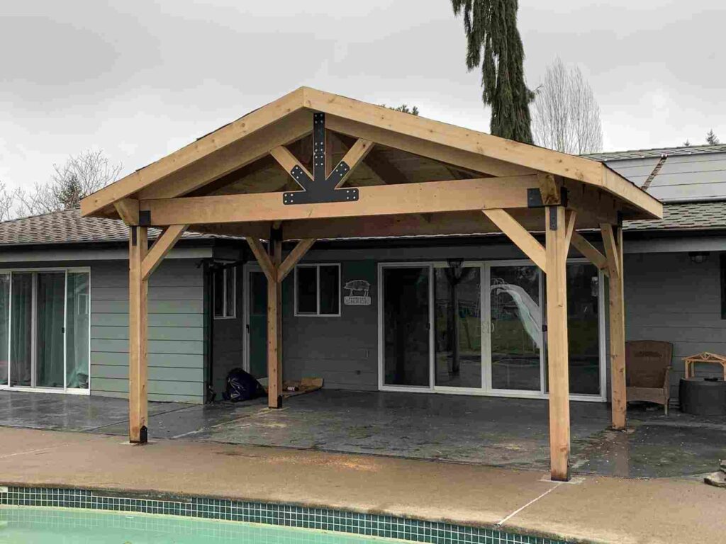 Wooden overhang on gray house and pool outside of the house and white trim glass window