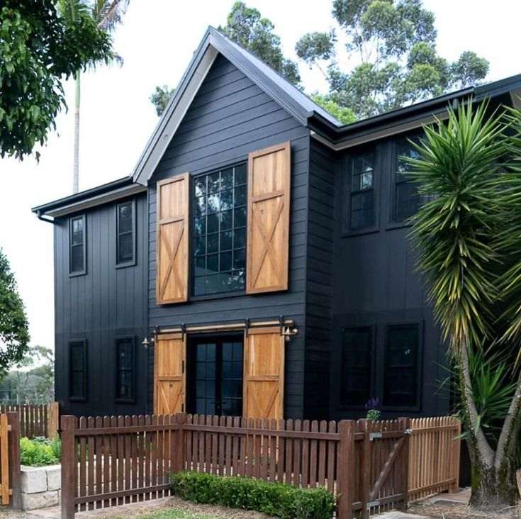 A wooden shutter and black house wood fencing around the house