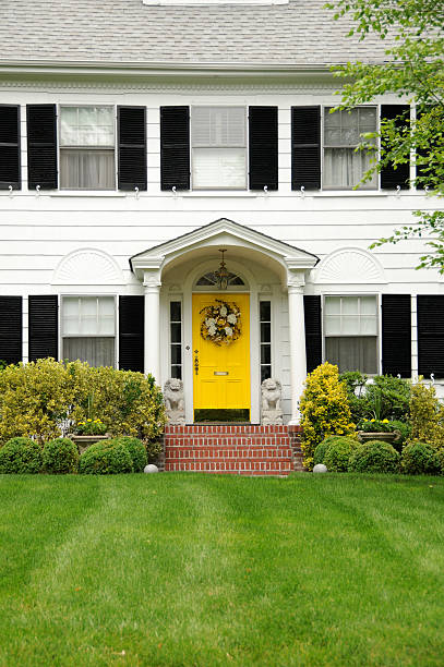 A white house and black windows and yellow front door
