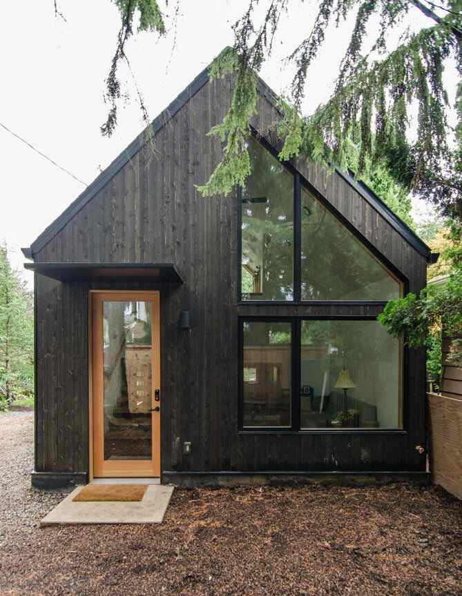 A black house with glass door and windows and at on the outside of the house