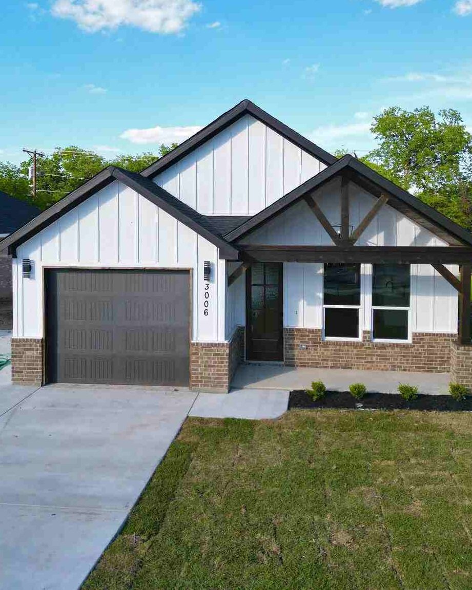 White house with black roof and wooden gable roof and stone base