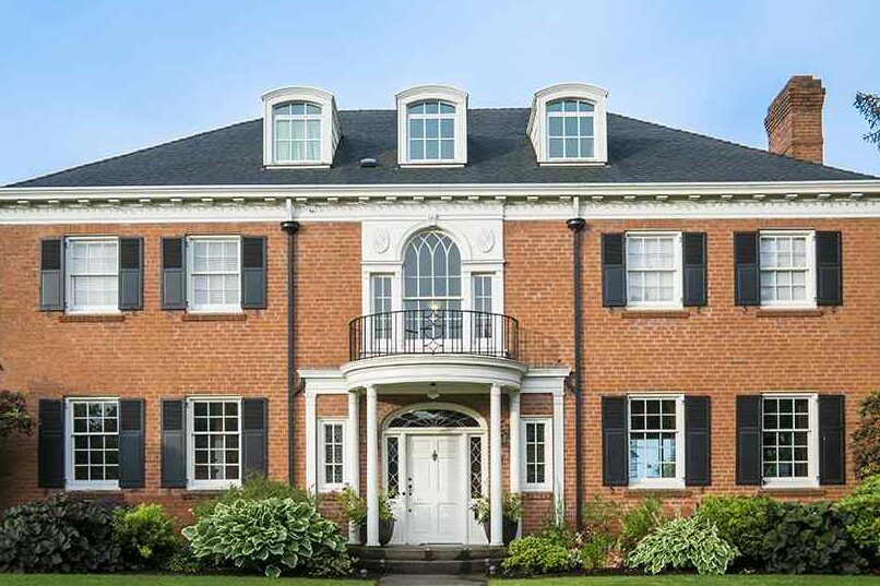 Red brick house with windows and black trim and white pillars and black shutter