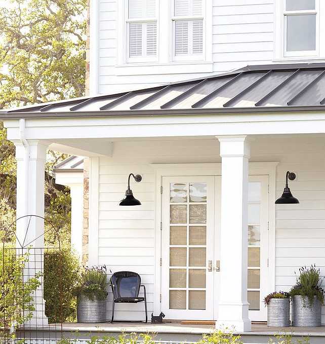 A white house with roof and black scones lights and glass white door 