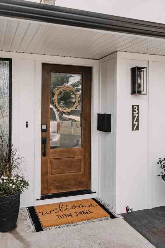 A white house with black mailbox and mat on the floor 