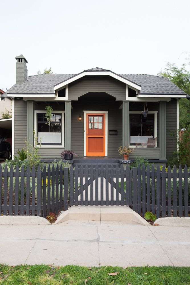 Black fence around house and wooden door and white trim roof and light on the wall