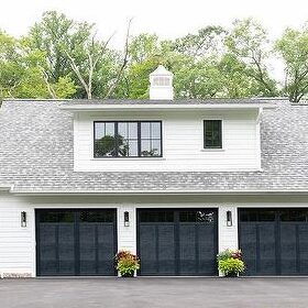 A white house with black garage door and a pathway