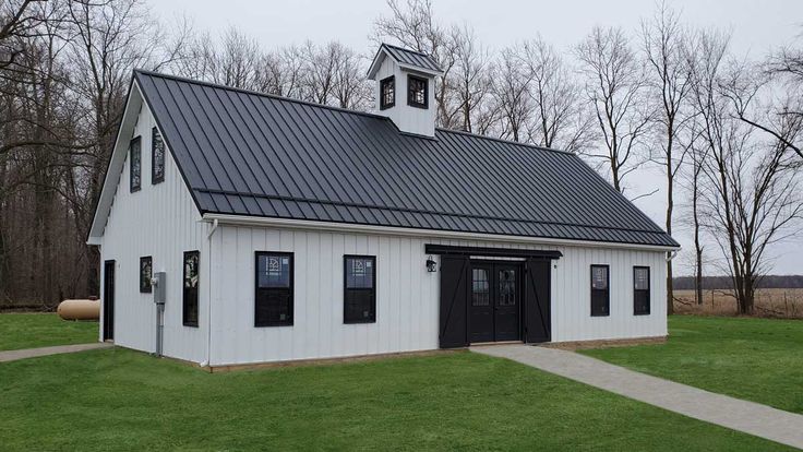 Black metal roof on white house and garden outside of the house