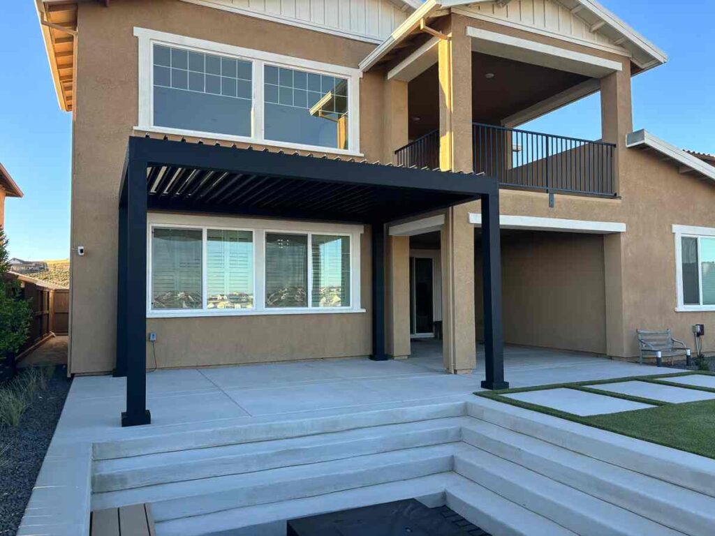Tan house with black pergola and white glass windows