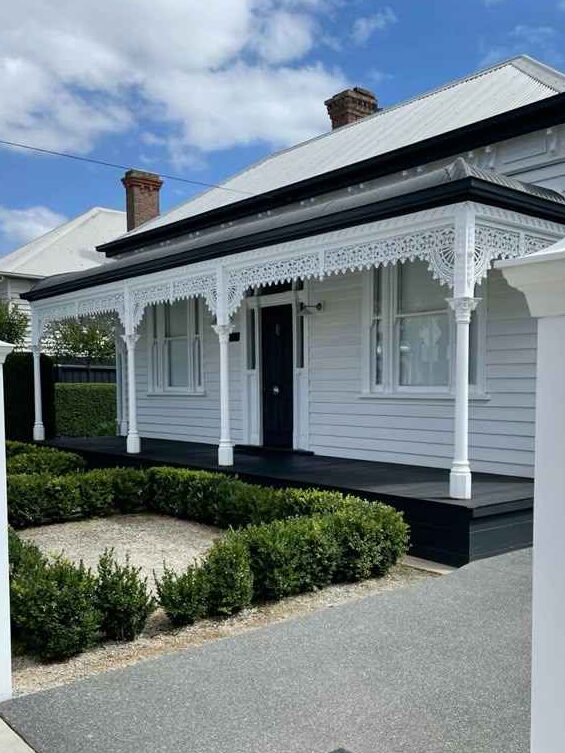 Black porch frontage on white house and white framed windows