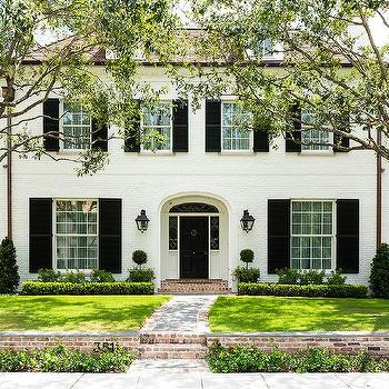 A white house with black gutters and black scones on wall