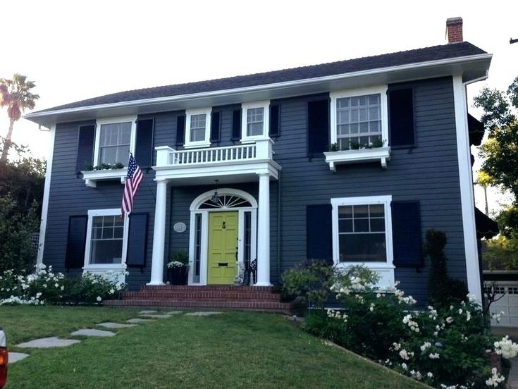 Black shutter with blue house and white trim windows and yellow door and garden outside of the house