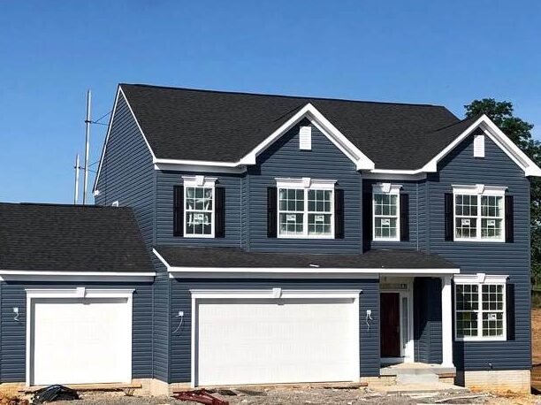 A blue house with black shutter and white garage door and white trim