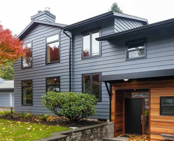 Blue house with black trim and black trim windows and garden outside of the house