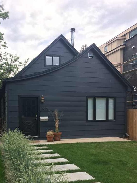 Blue house with black windows and garden outside of the house