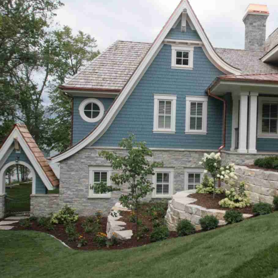 Blue house with stone base and white trim and garden outside of the house