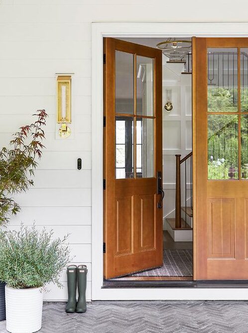 A white house with wooden house and plants outside of the door