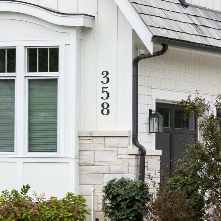 White house with white framed windows and brown number on the wall