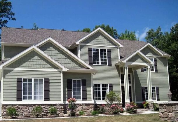 Green house with stone base and white trim