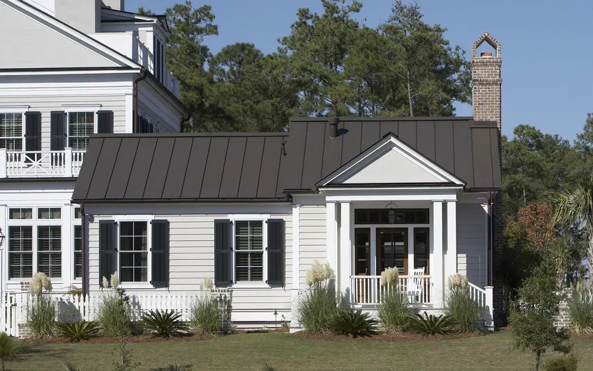 A white house with black roof and shutter and garden outside of the house 